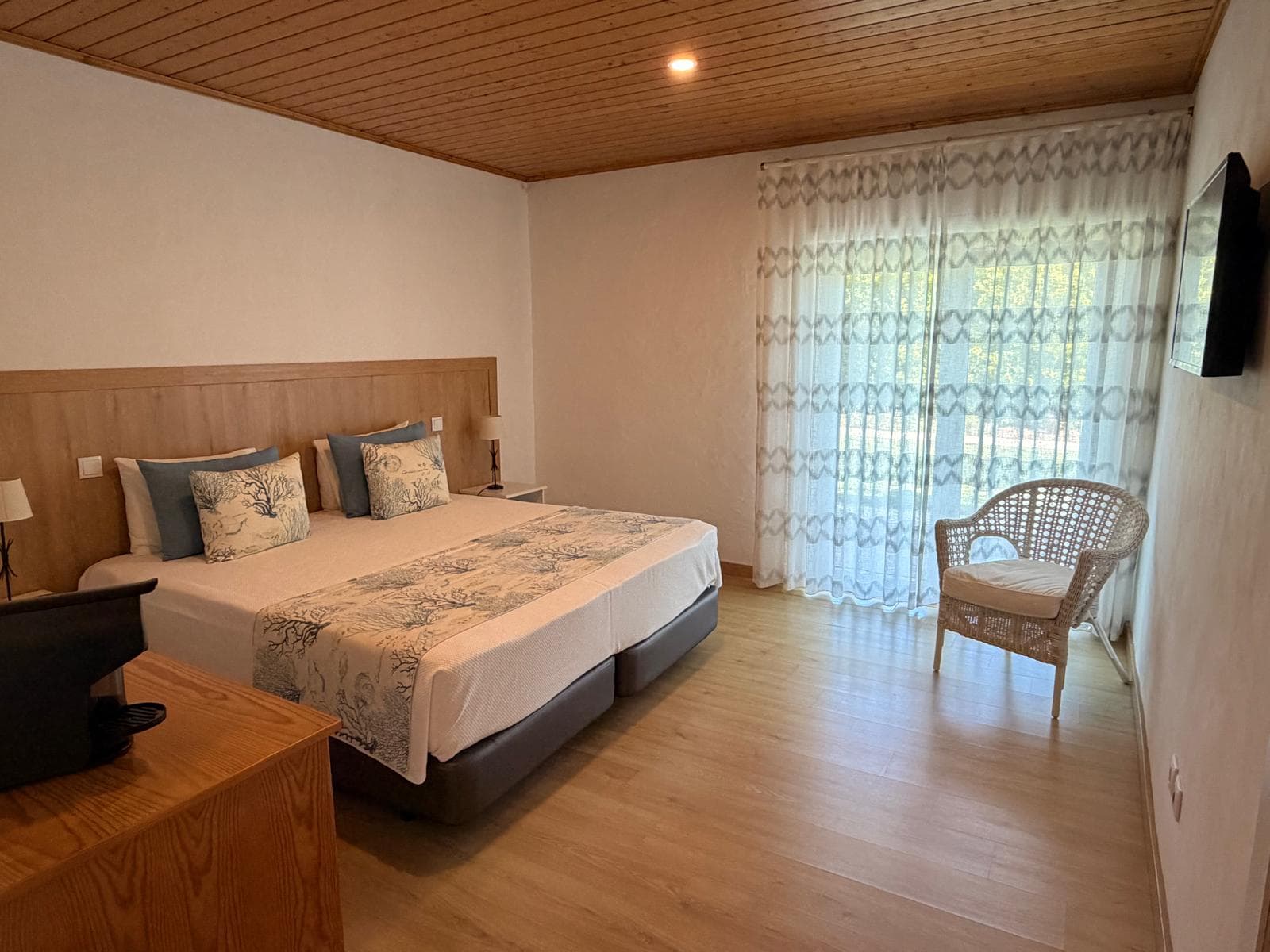 Quarto com porta envidraçada para a varanda e cortinado de linho