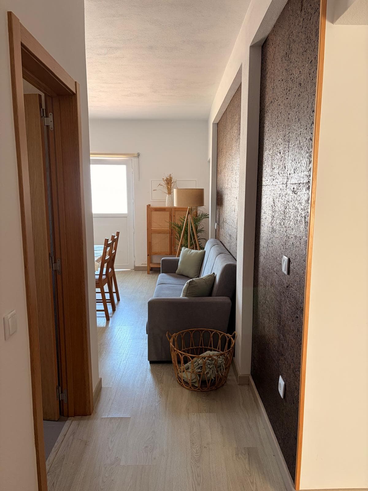 Corredor com parede de cortiça a abrir para a sala