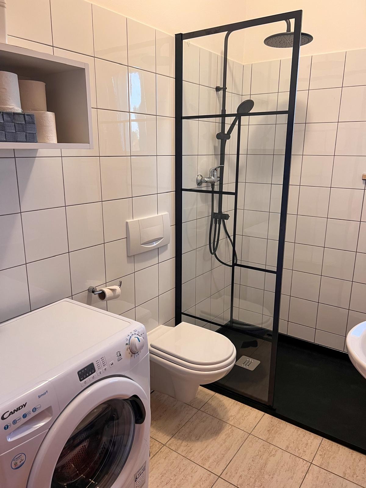 Casa de banho com duche e máquina de lavar roupa