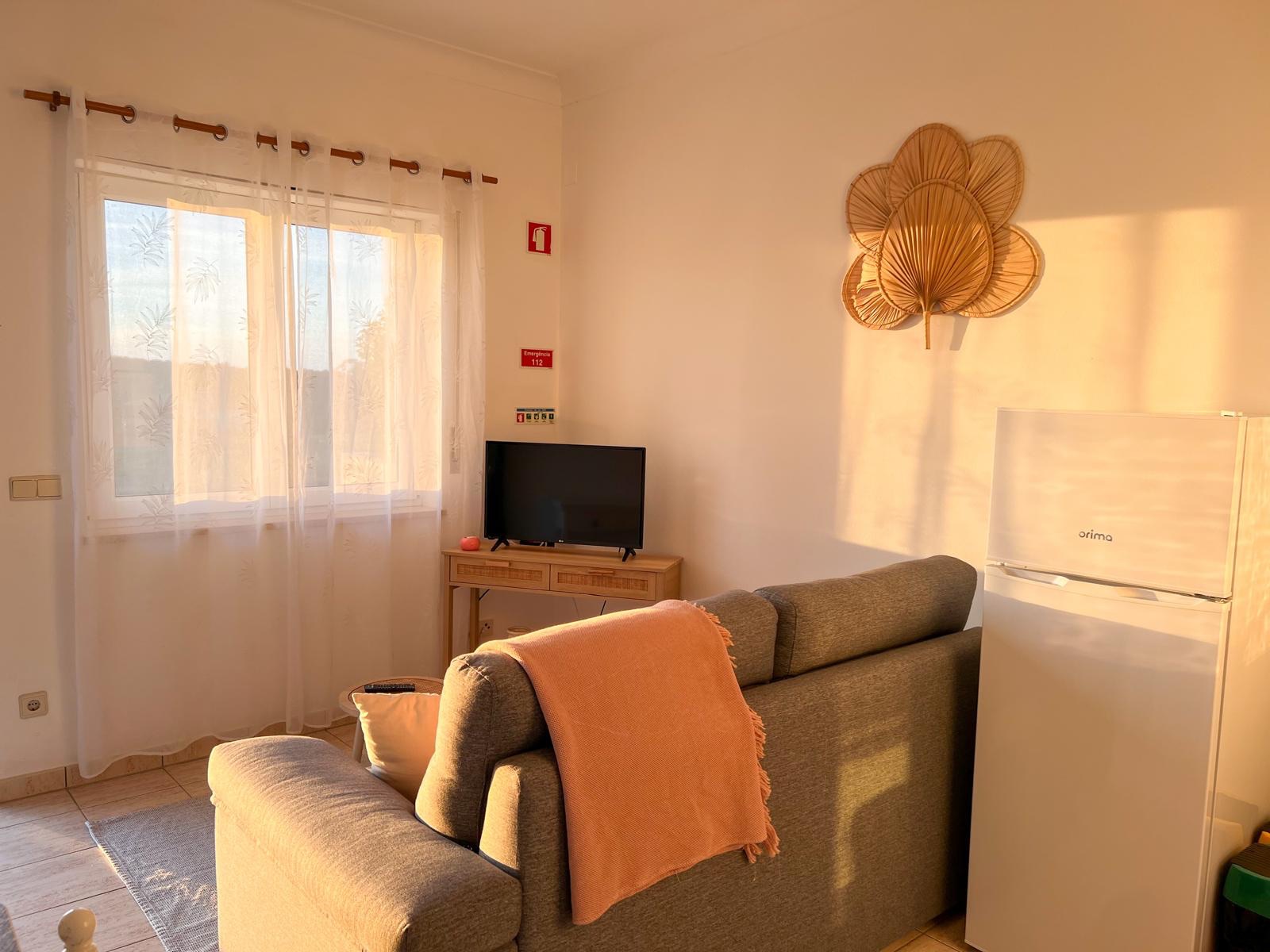 A sala com sofá, virada à janela