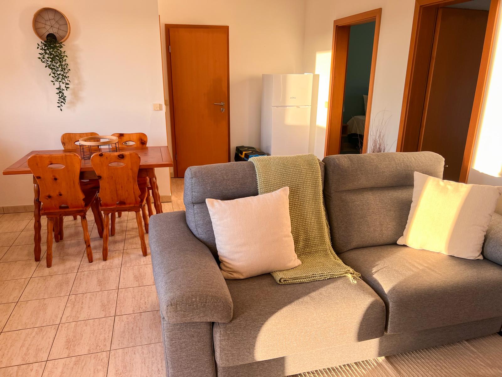 Mesa de jantar de pinho, com a sala e os quartos ao fundo